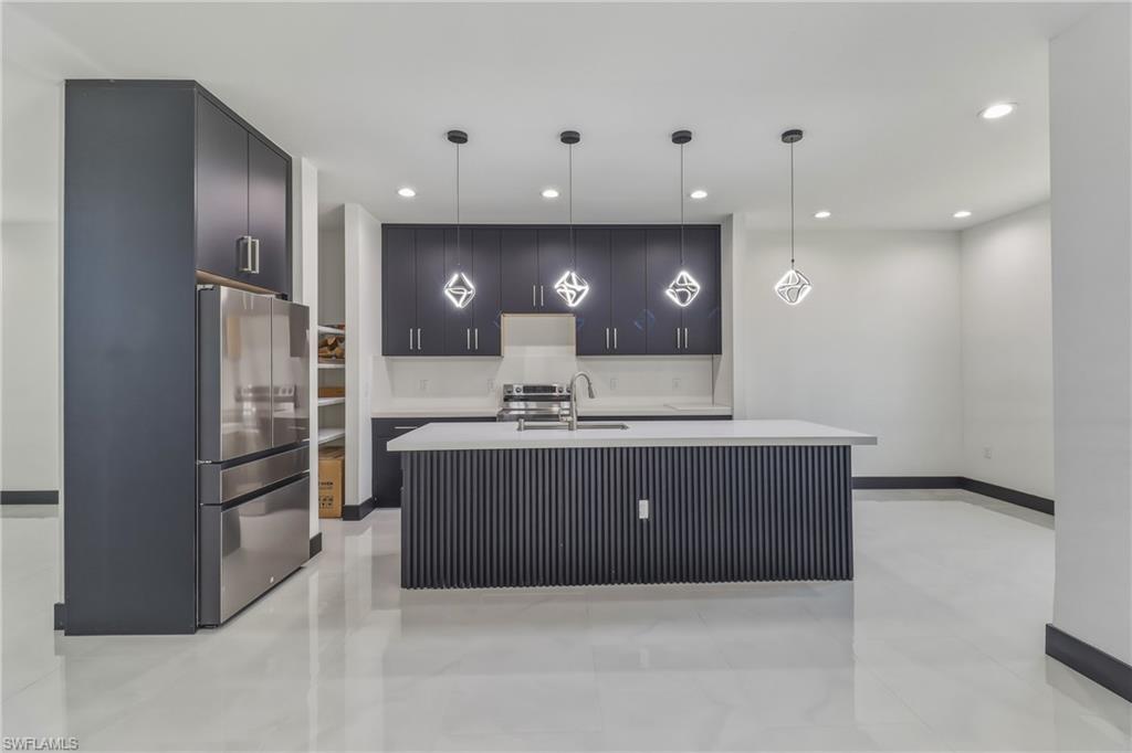 Kitchen featuring modern cabinets, stainless steel appliances, an island with sink, and pendant lighting
