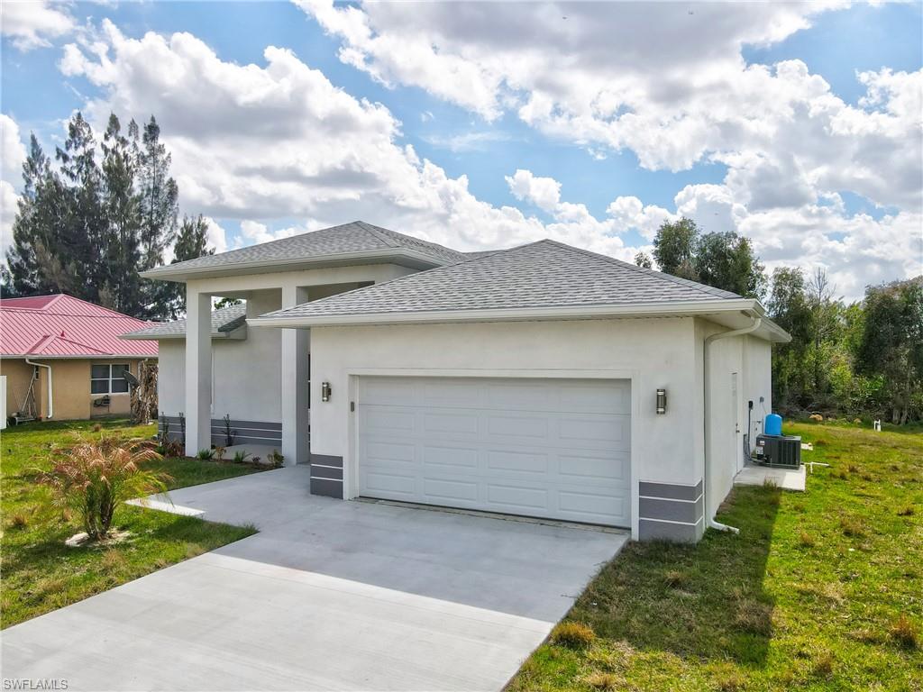 View of front of property featuring a garage, stucco siding, driveway, roof with shingles, and a front yard