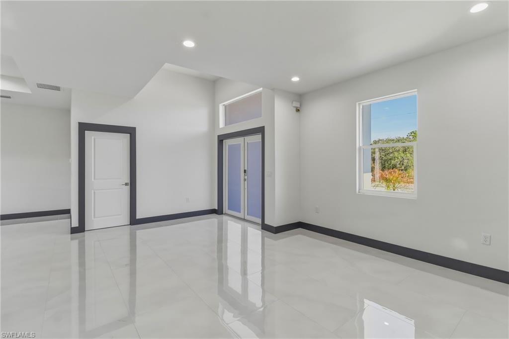 Empty room with french doors, recessed lighting, and light tile patterned floors