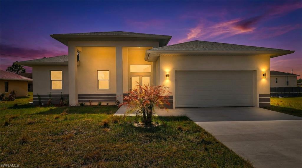 Prairie-style house with a garage, concrete driveway, a yard, and stucco siding
