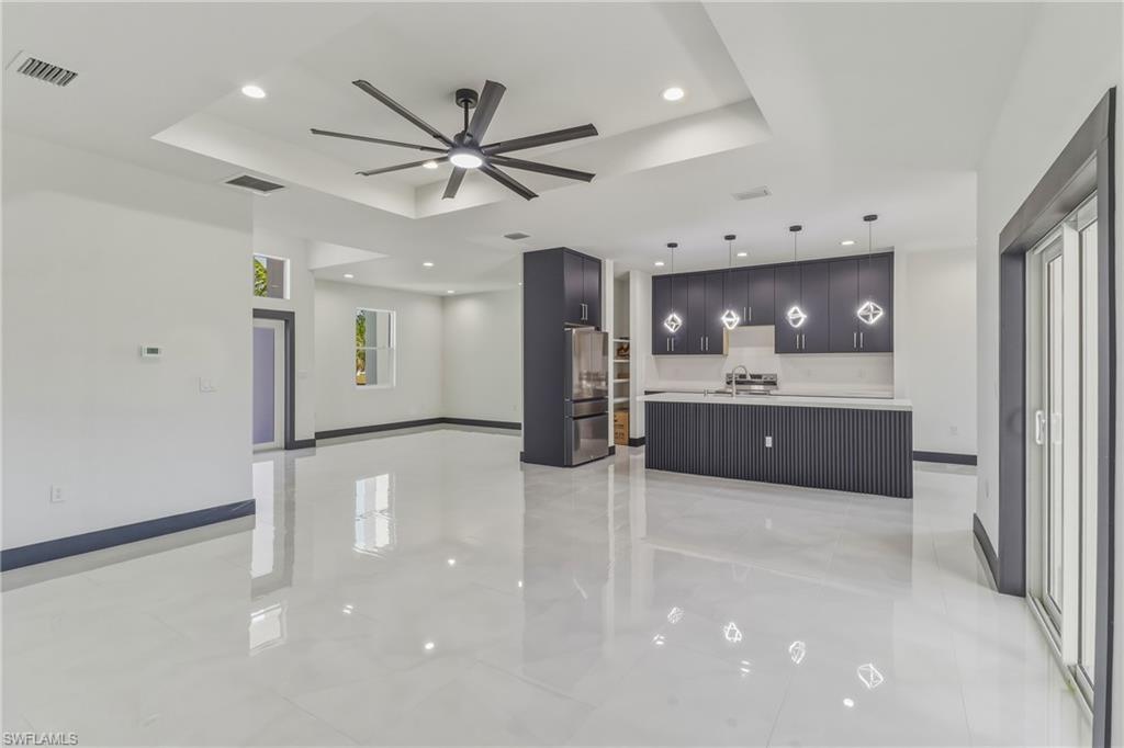 Kitchen featuring a ceiling fan, hanging light fixtures, a raised ceiling, modern cabinets, and light countertops