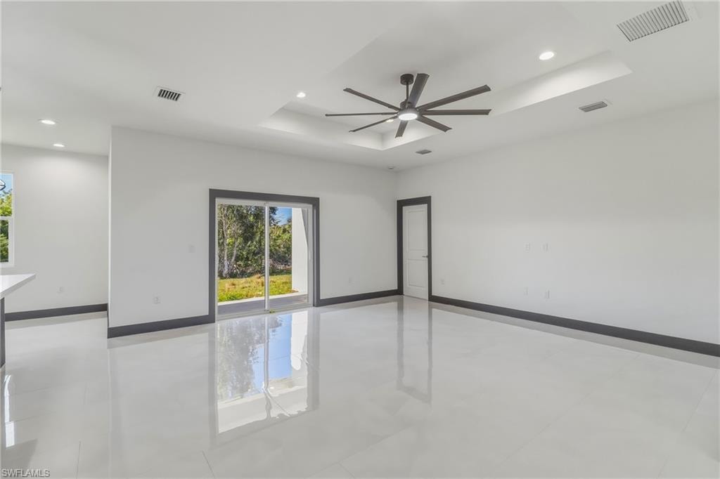 Spare room featuring a raised ceiling, a ceiling fan, recessed lighting, and light tile patterned floors