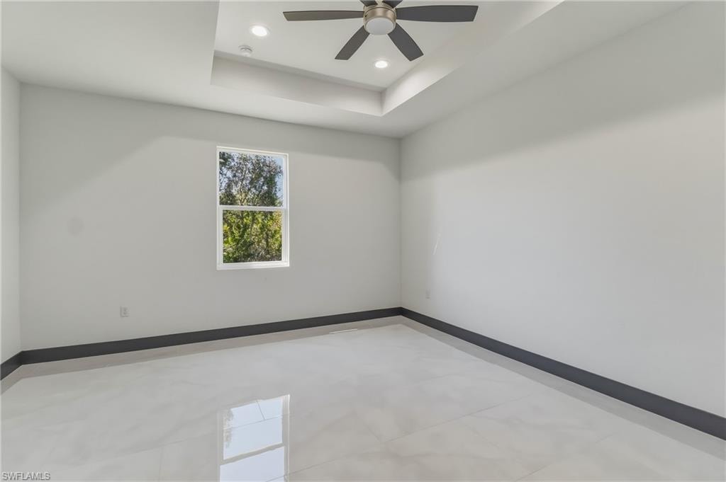 Empty room featuring a tray ceiling, recessed lighting, and a ceiling fan