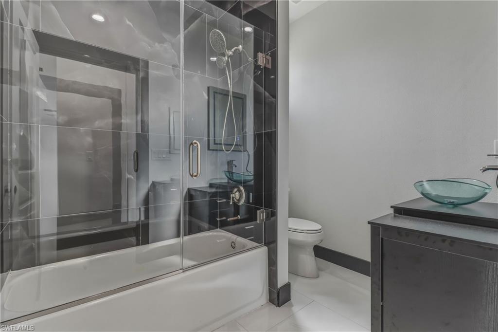 Bathroom featuring vanity, combined bath / shower with glass door, and light tile patterned flooring