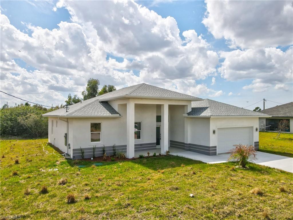 Prairie-style home featuring stucco siding, a front yard, an attached garage, concrete driveway, and a shingled roof
