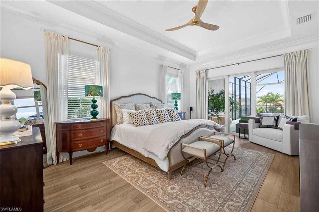 Bedroom featuring access to outside, light wood finished floors, ceiling fan, ornamental molding, and a tray ceiling