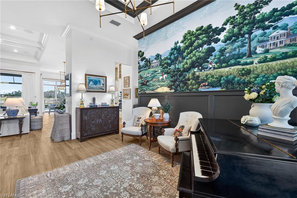Sitting room featuring a chandelier, wood finished floors, crown molding, and a high ceiling