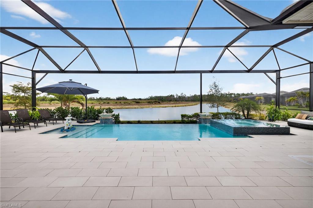 Combined pool / hot tub featuring a sunroom, a lanai, a water view, and a patio