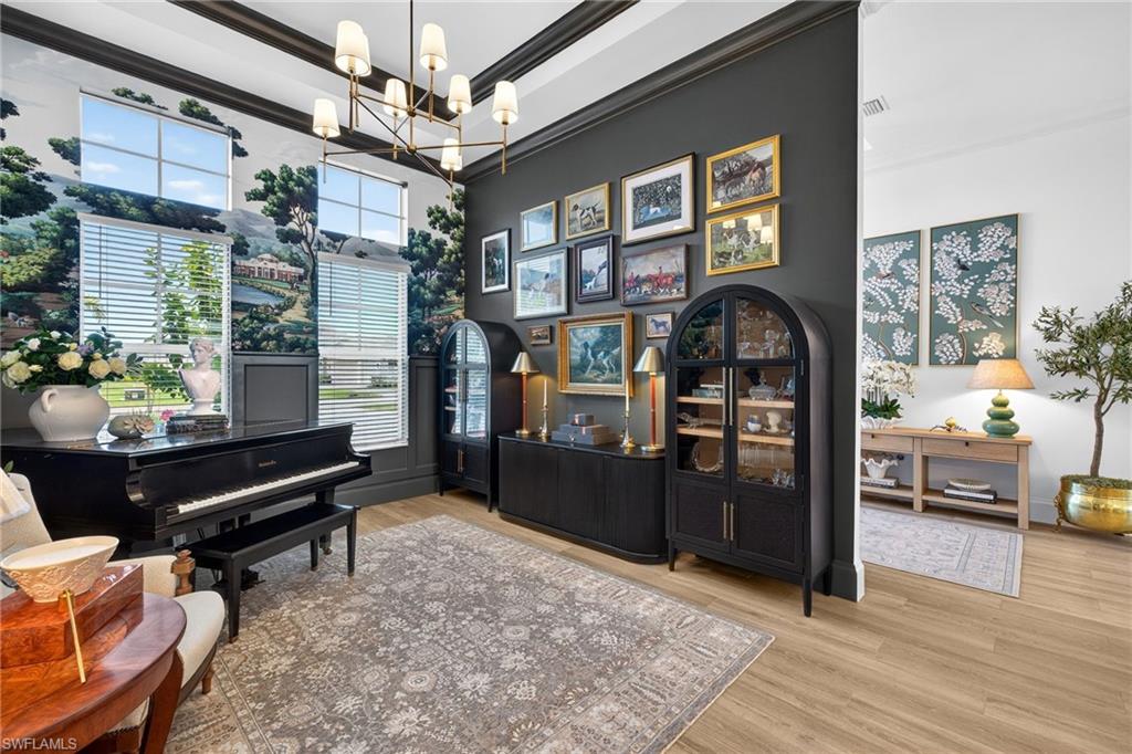 Office featuring light wood-style floors, ornamental molding, a chandelier, and a high ceiling
