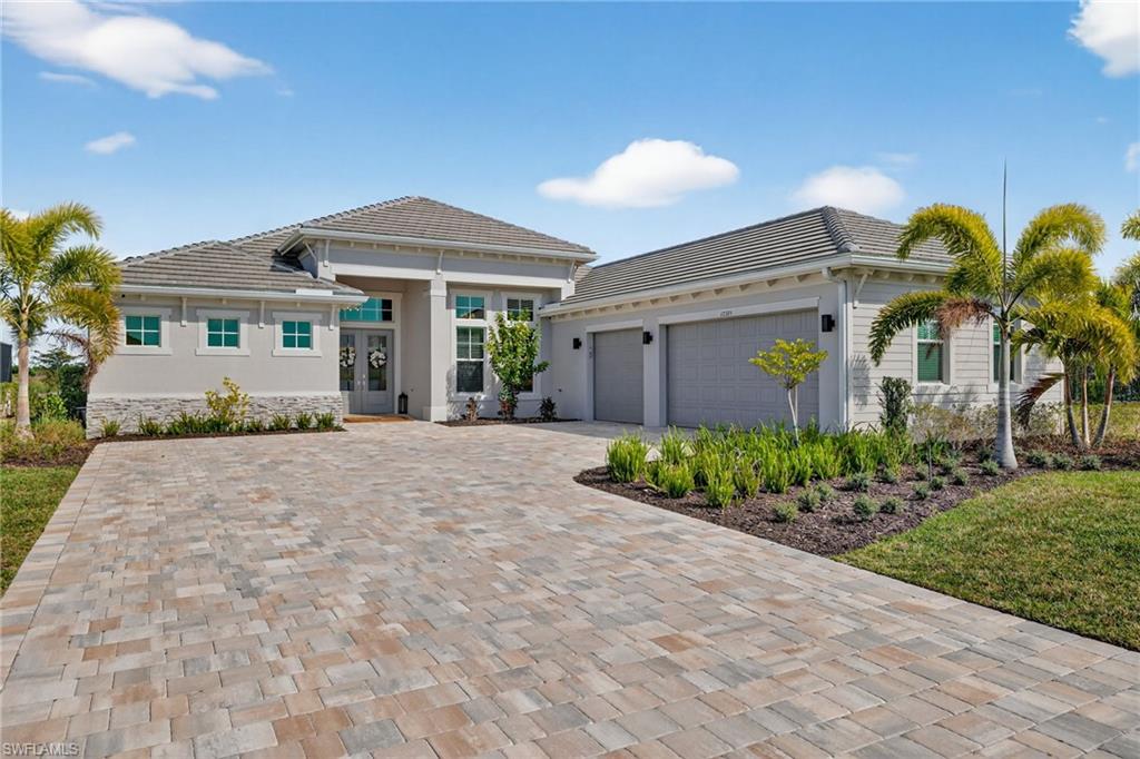 View of front of house with french doors, an attached garage, decorative driveway, a tile roof, and stucco siding