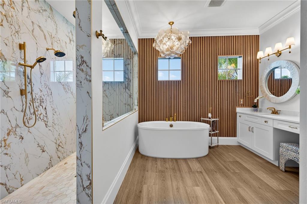 Bathroom with a marble finish shower, a soaking tub, light wood-style floors, vanity, and ornamental molding