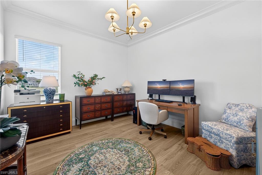 Office with light wood-style floors, a chandelier, and crown molding