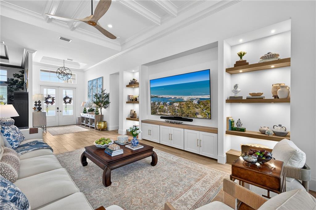 Living area with built in features, light wood-style flooring, french doors, a ceiling fan, and coffered ceiling