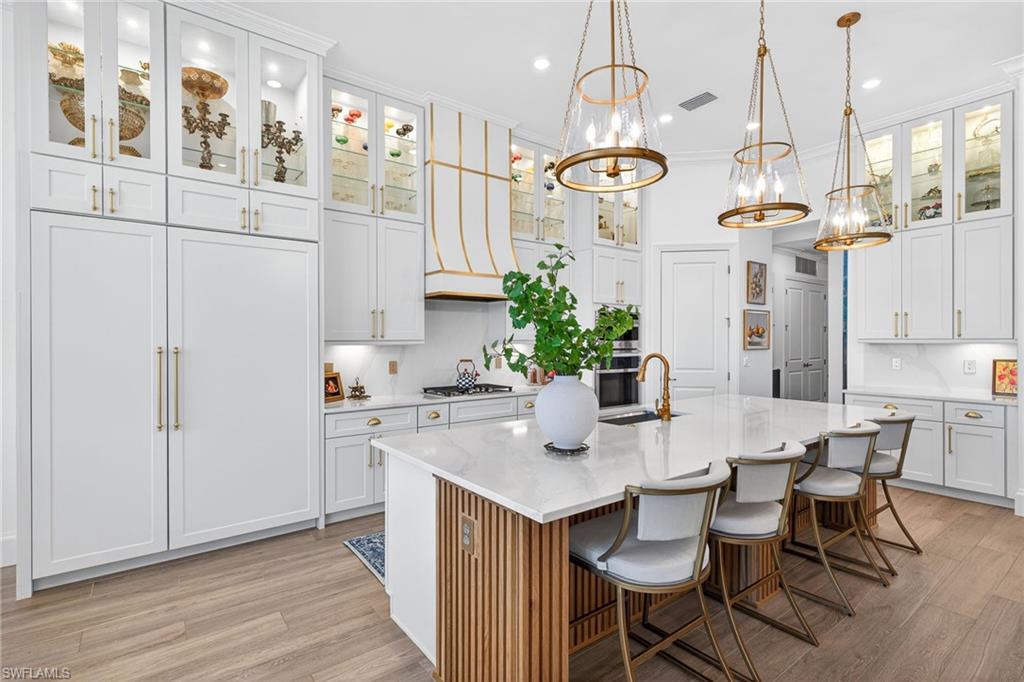 Kitchen featuring glass fronted cabinets, light stone countertops, white cabinets, and crown molding