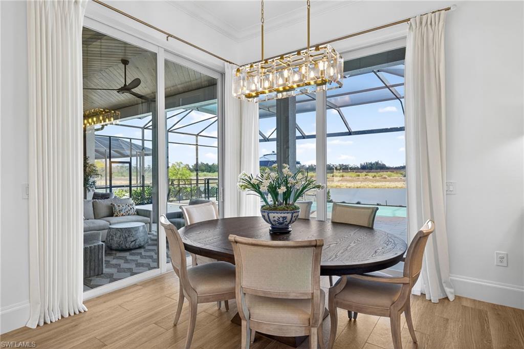 Dining space featuring a sunroom, light wood-style floors, ornamental molding, a ceiling fan, and a water view
