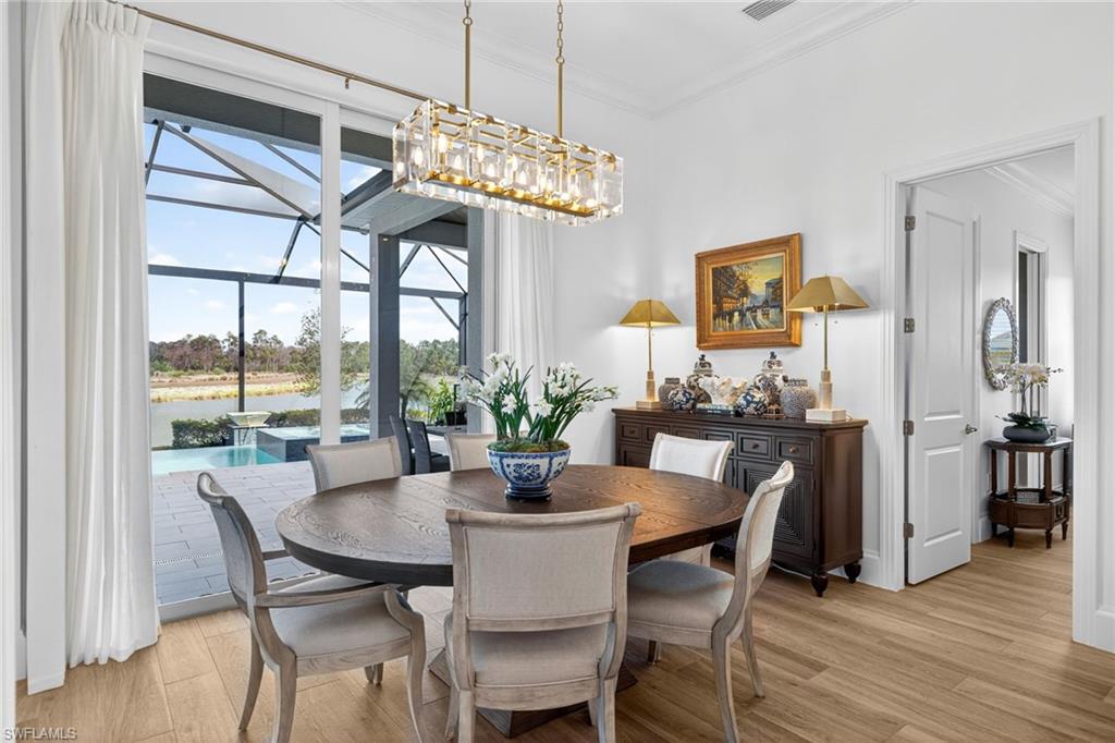 Dining area with light wood-style floors, ornamental molding, and a sunroom
