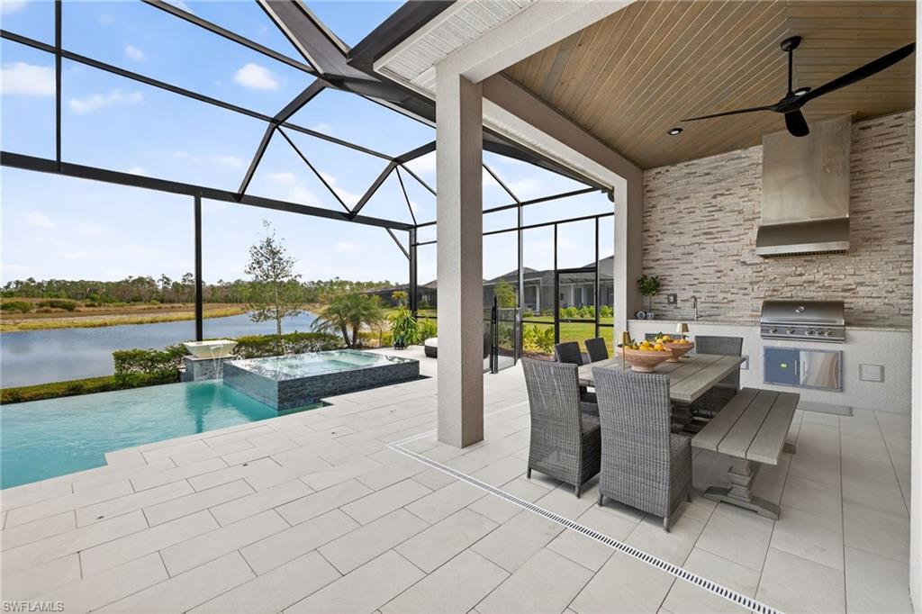 View of patio / terrace with a sunroom, an outdoor kitchen / dining area, glass enclosure, a water view, and ceiling fan