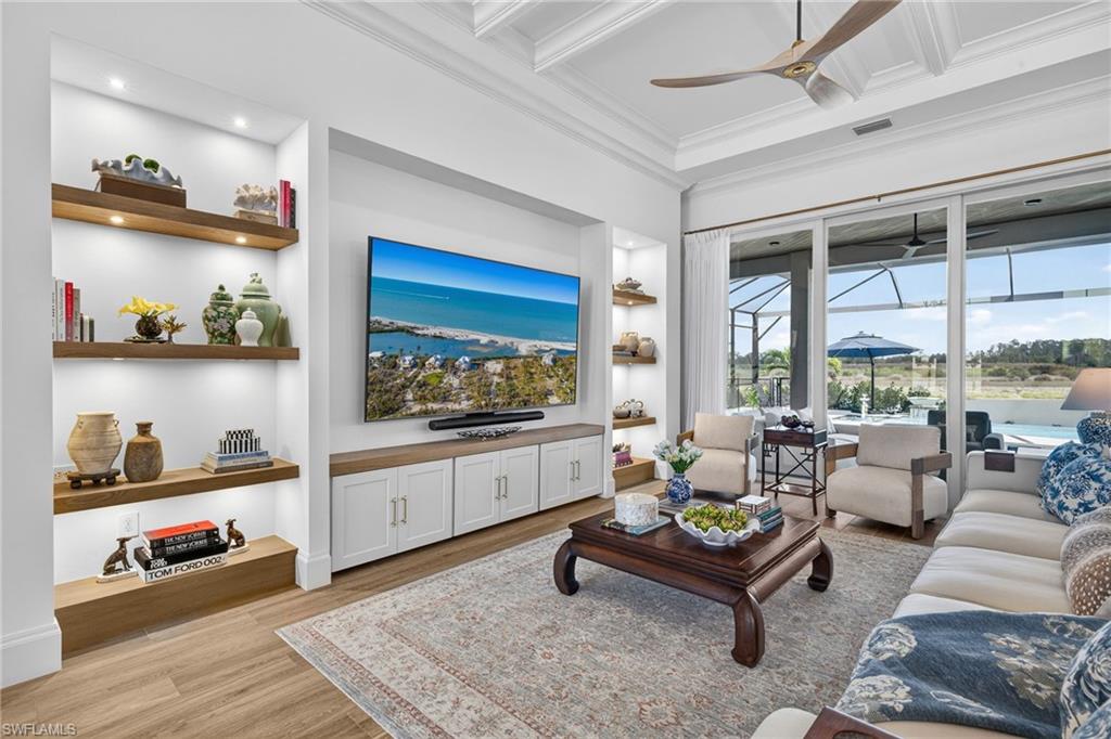 Living room with a sunroom, a ceiling fan, built in features, coffered ceiling, and light wood finished floors