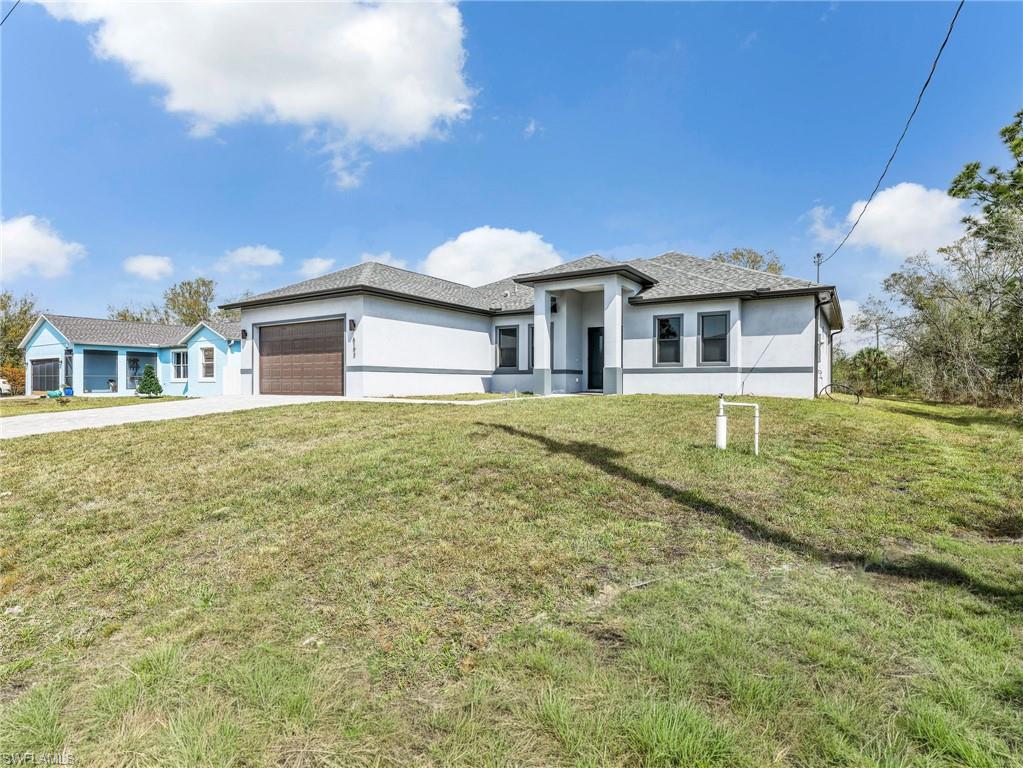 Prairie-style house with a front yard, a garage, stucco siding, and concrete driveway