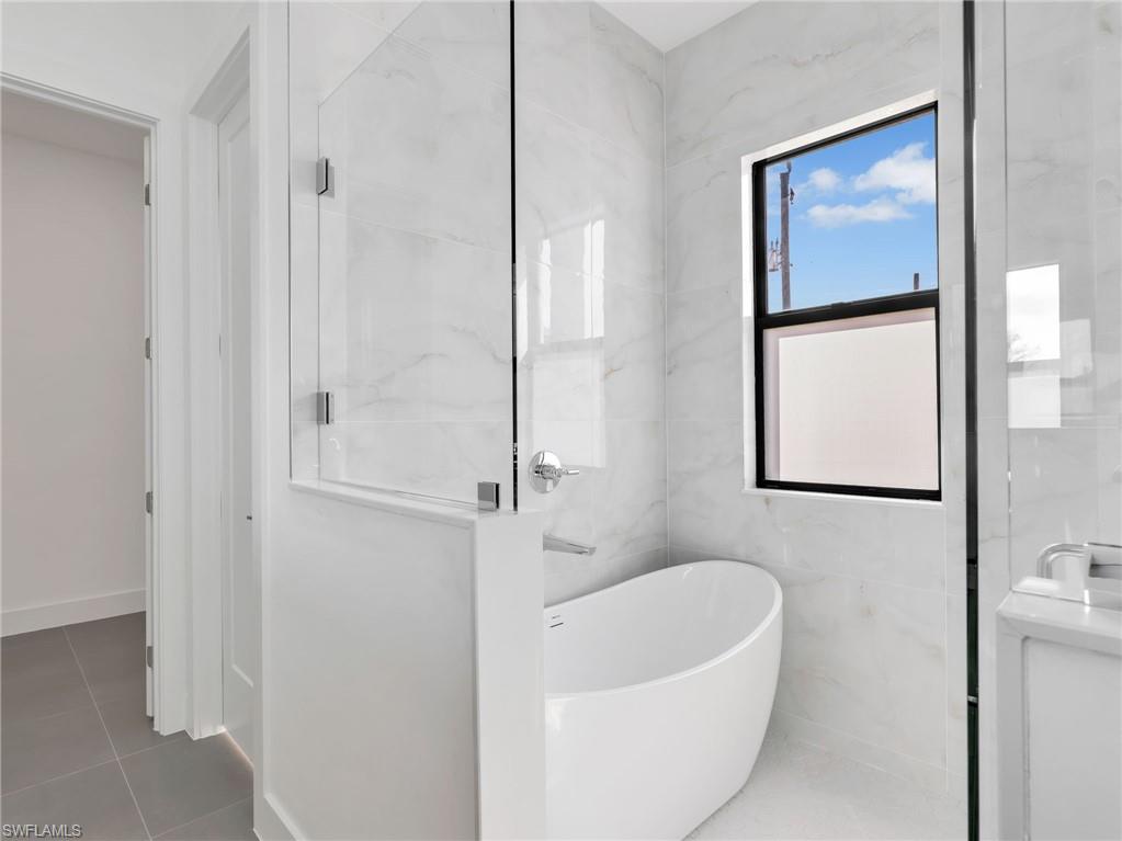 Full bathroom featuring a soaking tub, tile walls, and tile patterned floors