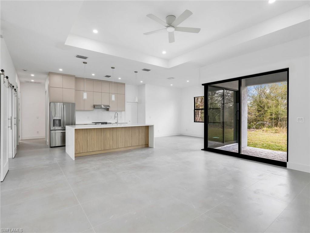 Two tone kitchen featuring open floor plan, a barn door, modern cabinets, hanging light fixtures, and a tray ceiling
