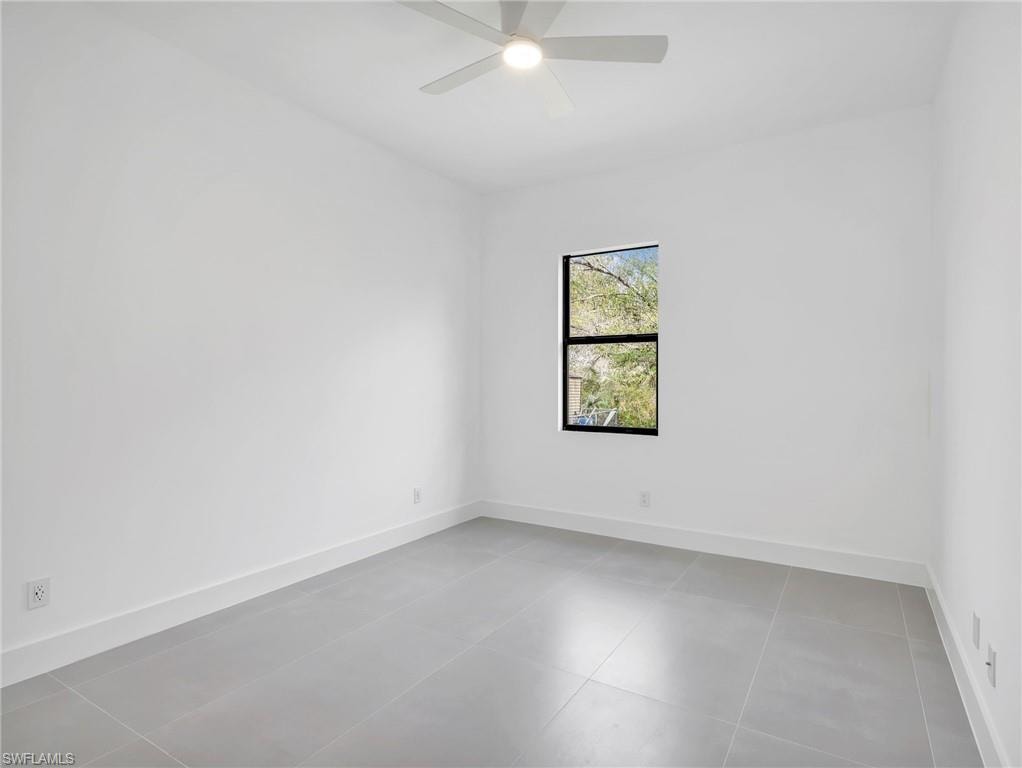 Empty room with a ceiling fan and light tile patterned floors