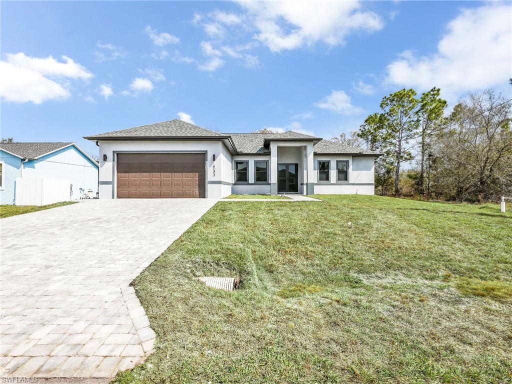 Prairie-style home with a garage, stucco siding, decorative driveway, a front yard, and roof with shingles