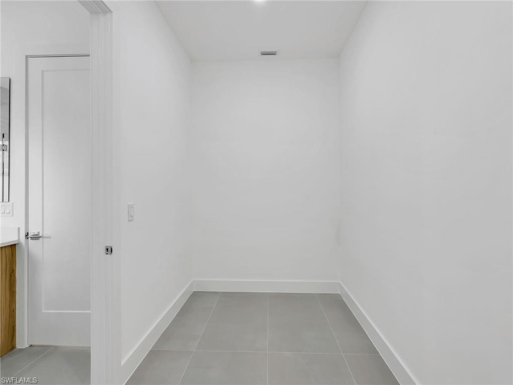 Laundry room featuring light tile patterned flooring and baseboards