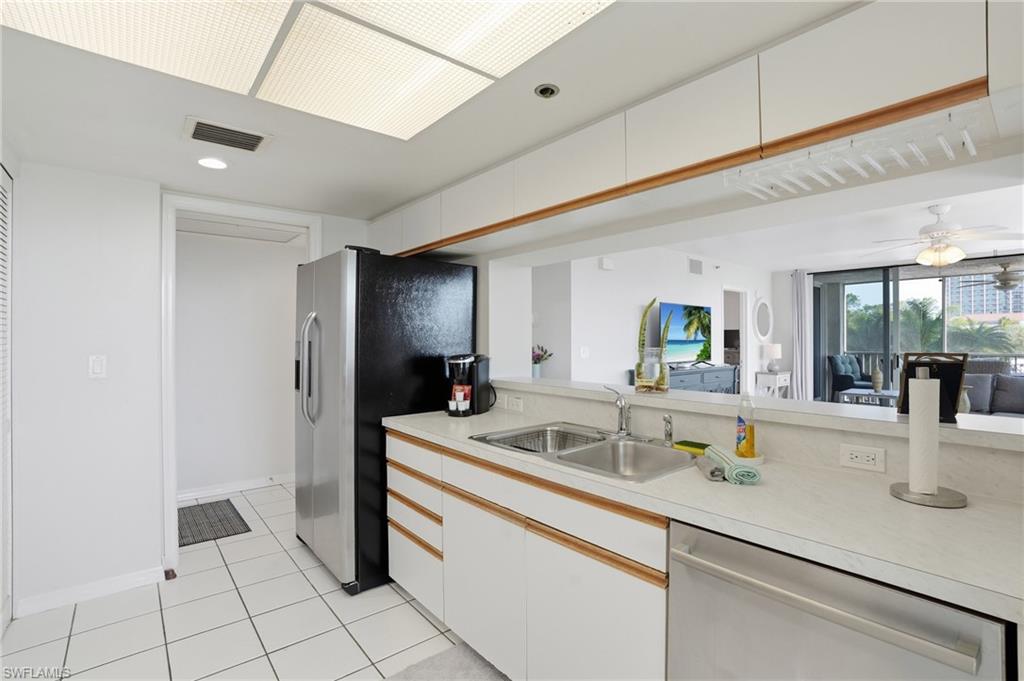 Kitchen featuring light countertops, two tone cabinets, stainless steel appliances, light tile patterned floors, and recessed lighting
