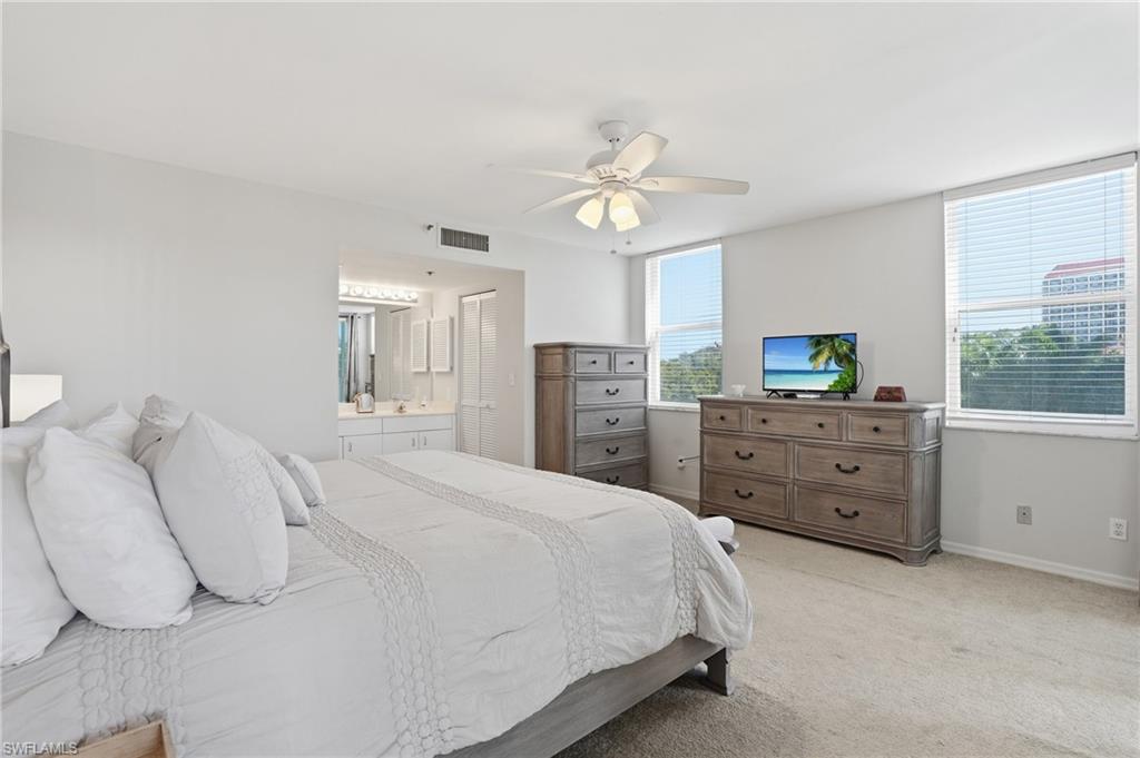 Bedroom featuring light carpet, ceiling fan, and ensuite bath