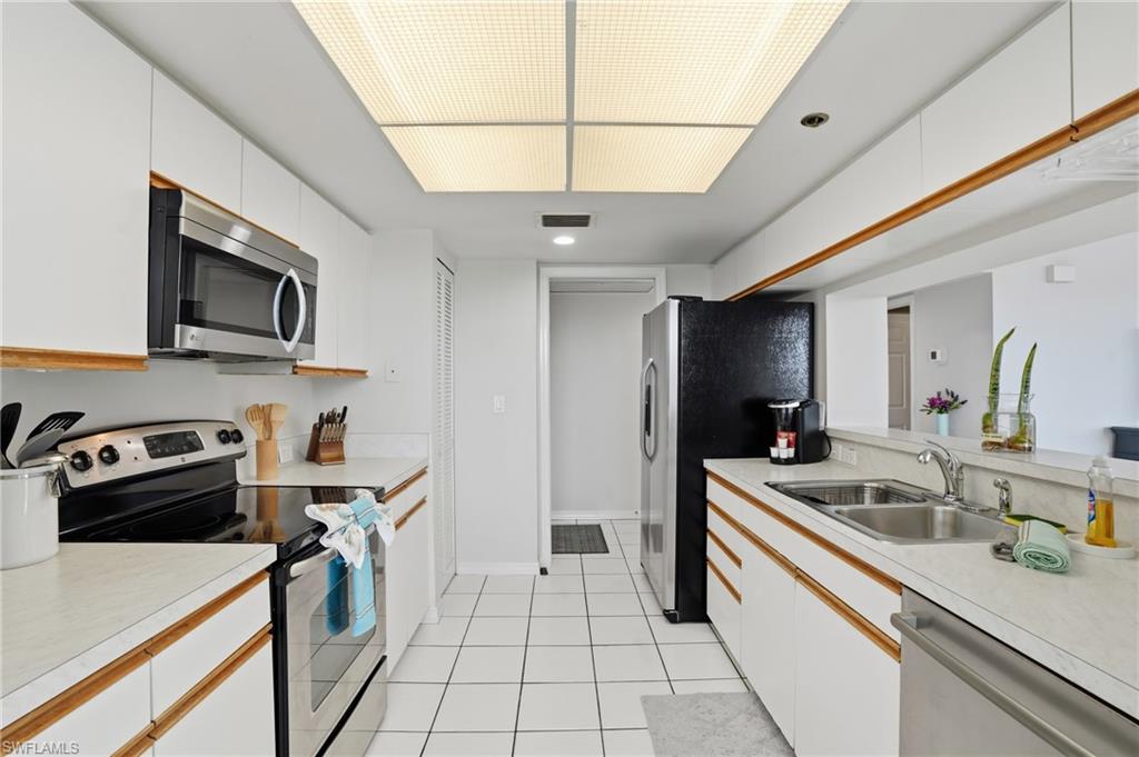 Kitchen with stainless steel appliances, light countertops, two tone cabinetry, light tile patterned floors, and recessed lighting