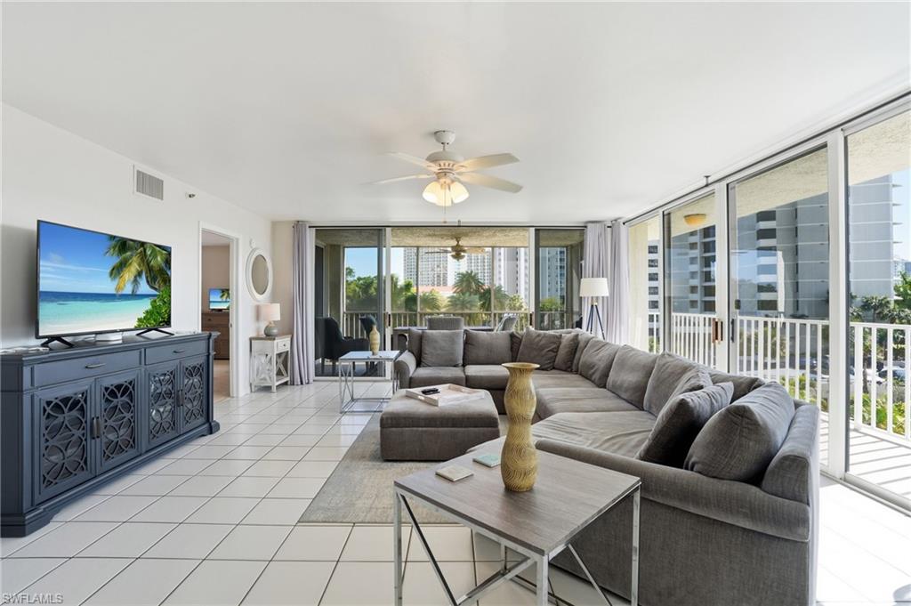 Living area with a ceiling fan, light tile patterned floors, and floor to ceiling windows