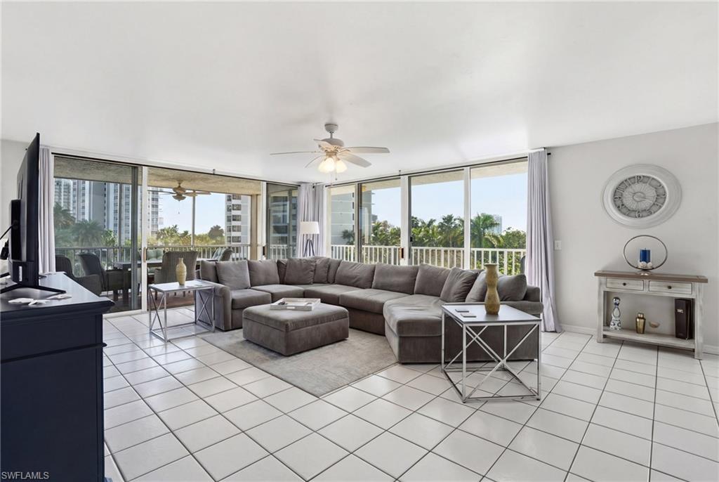 Living area with light tile patterned floors, a ceiling fan, and expansive windows