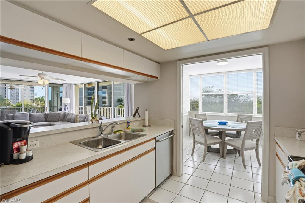 Kitchen with light countertops, open floor plan, ceiling fan, light tile patterned flooring, and stainless steel dishwasher