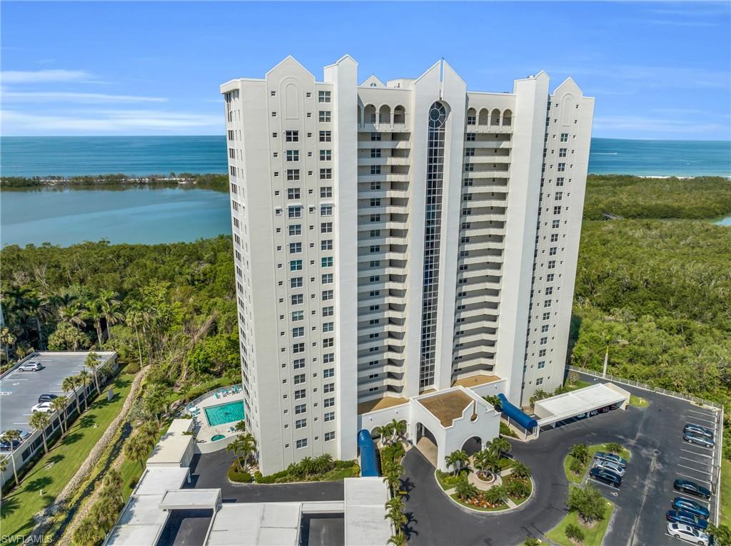 View of apartment building / complex featuring a water view and uncovered parking