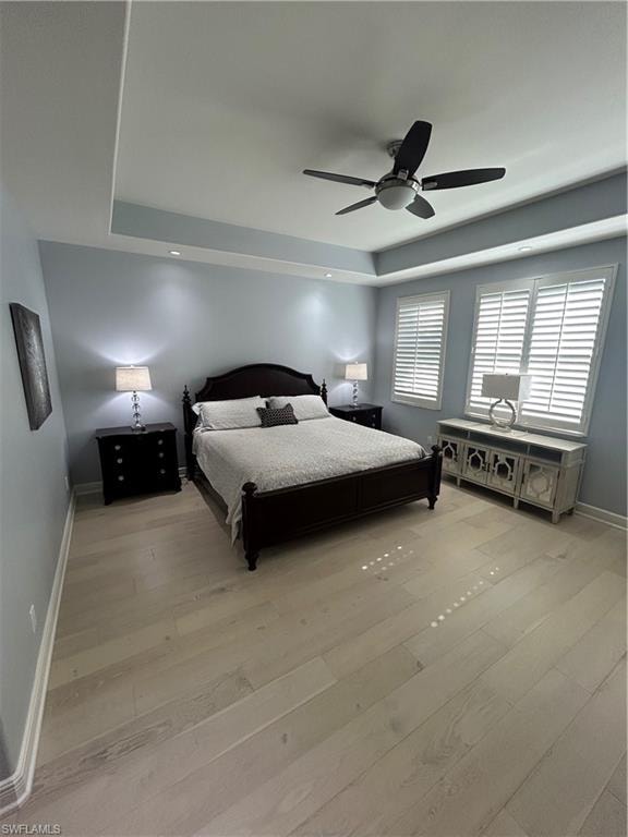 Primary Bedroom featuring a tray ceiling, a ceiling fan, recessed lighting and light wood-style flooring