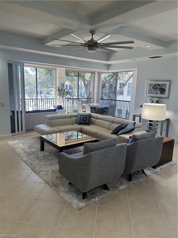 Living area with ceiling fan, light tile patterned flooring, and beam ceiling