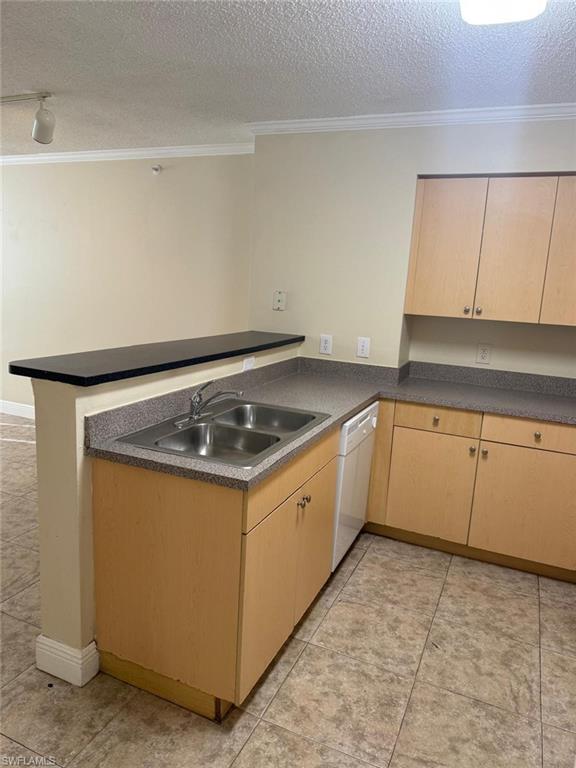 Kitchen with dark countertops, a peninsula, ornamental molding, a textured ceiling, and dishwasher