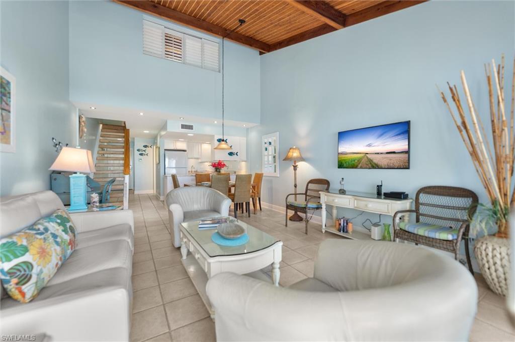 Living room featuring light tile patterned flooring and a high wood beamed ceiling