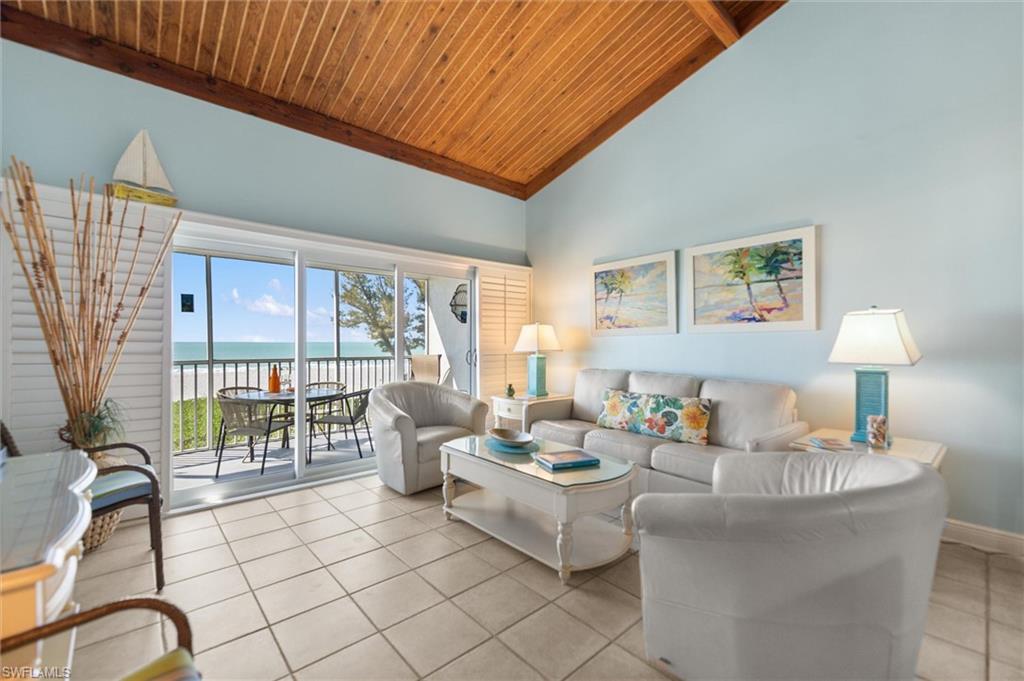Living room with a high wooden beamed ceiling, a water view, and light tile patterned floors