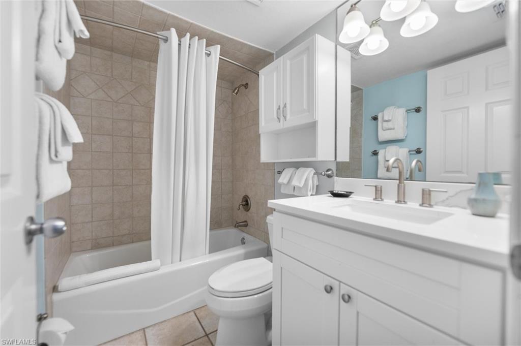 Bathroom with vanity, shower / bath combo with shower curtain, and light tile patterned floors