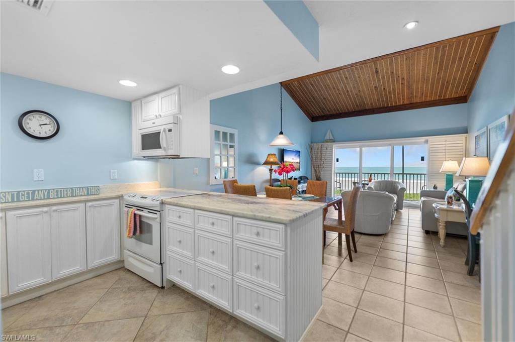 Kitchen with white appliances, a peninsula, pendant lighting, open floor plan, and light tile patterned floors