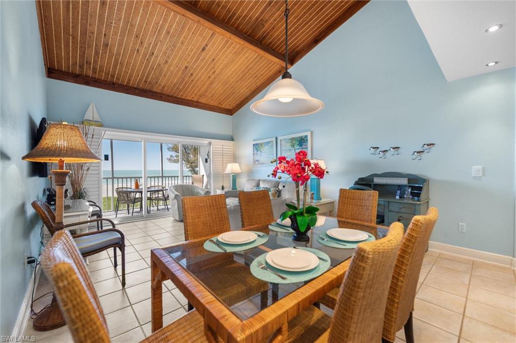 Dining room featuring light tile patterned floors, a high wood beamed ceiling, and a water view