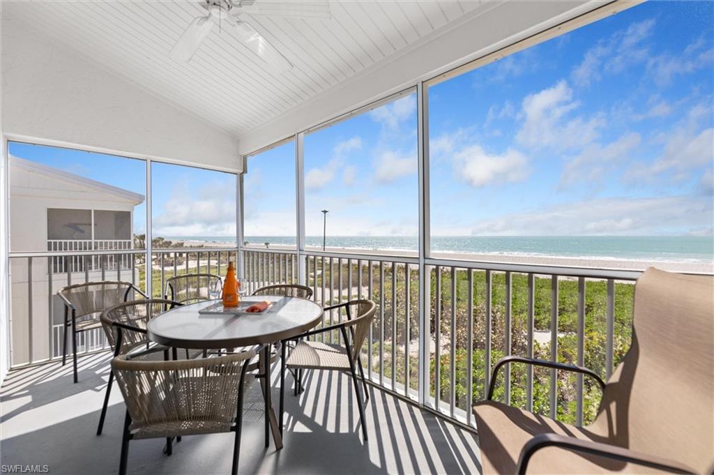 Sunroom featuring view of water and beach, lofted ceiling, and finished concrete floors