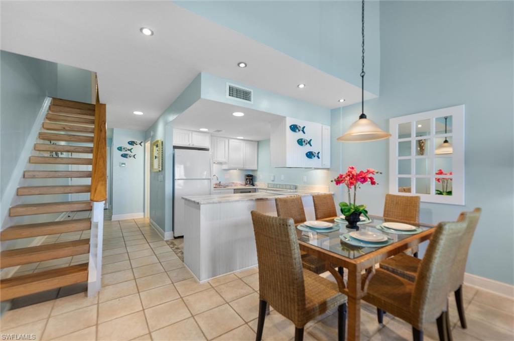 Dining room with light tile patterned floors, a high ceiling, and recessed lighting