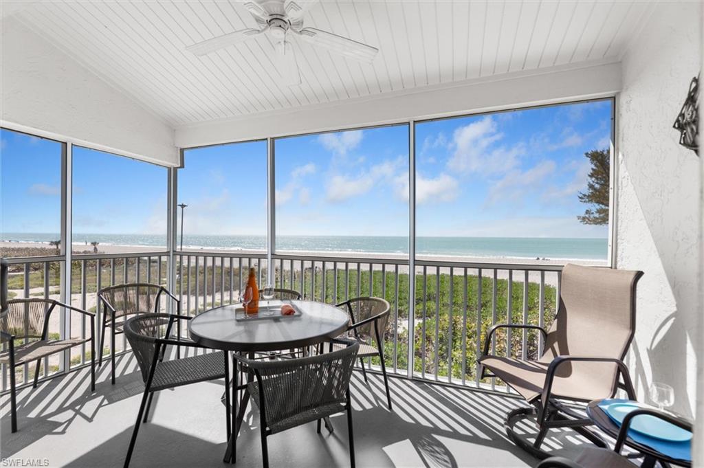 Sunroom with view of water and beach, a textured wall, and concrete floors