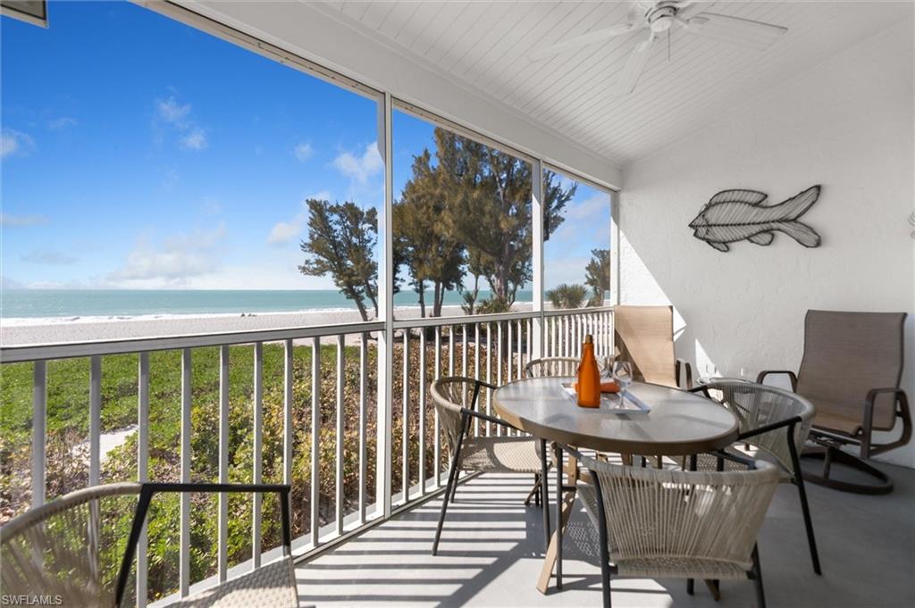 Sunroom featuring view of water and beach, ceiling fan, a balcony, vaulted ceiling, and outdoor dining area