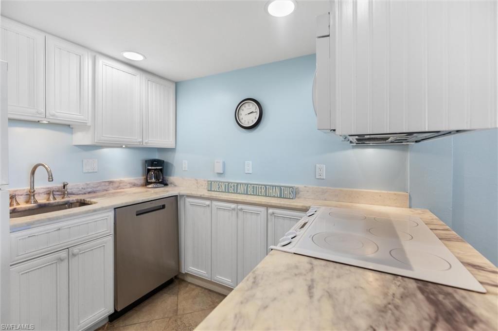 Kitchen featuring white appliances, white cabinetry, light stone counters, and light tile patterned floors