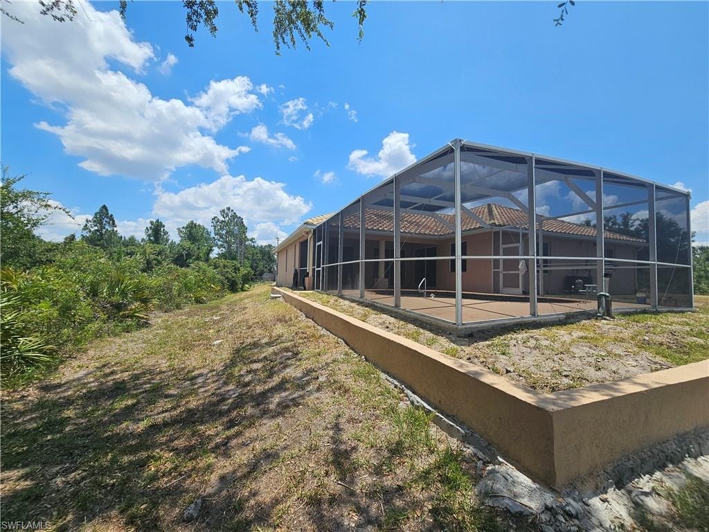 View of yard with glass enclosure and a patio area