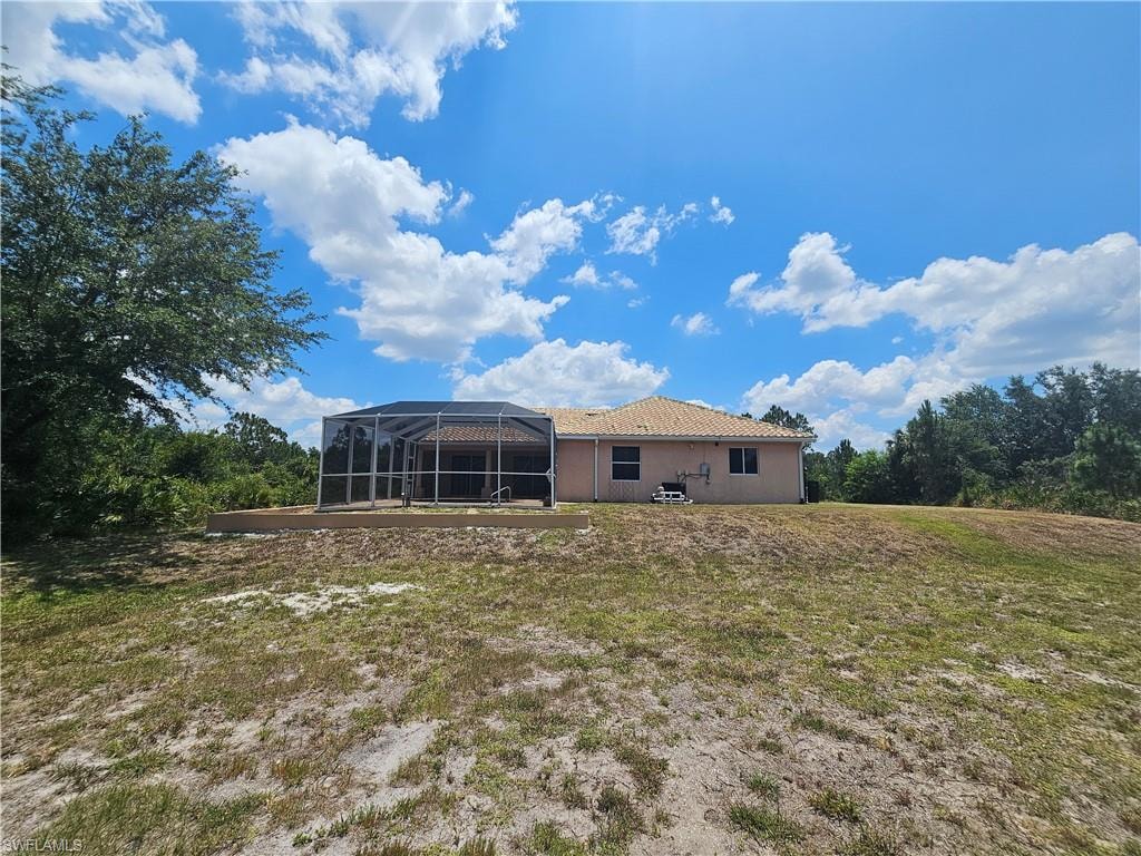 Rear view of property with a lanai and a lawn
